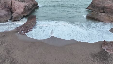 Aerial-drone-top-down-shot-over-sea-waves-crashing-along-Gadani-Beach-in-Balochistan,-Pakistan-during-evening-time