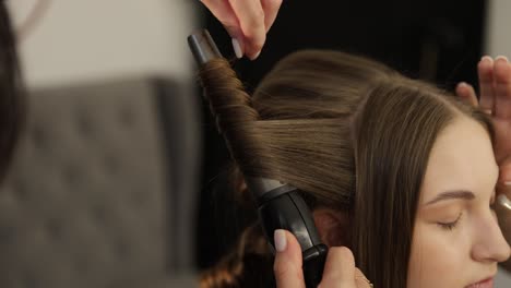 a stylist expertly curling beautiful hair using a curling iron, showcasing modern styling techniques