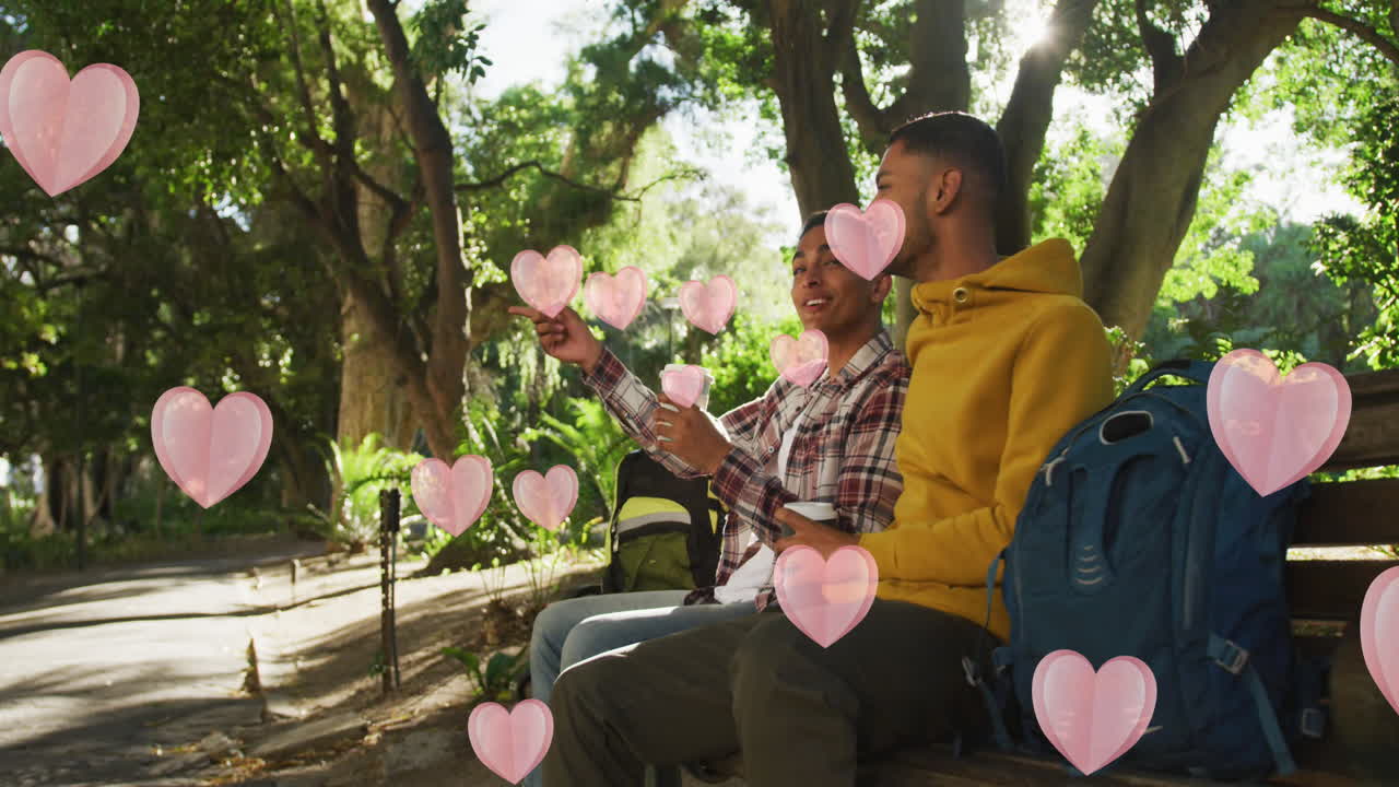 파크에서 커피를 마시며 행복한 다양한 동성애 남성 커플을 떠다니는 분홍색 심장의 애니메이션
