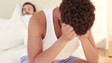 hombre con dolor de cabeza sentado en la cama