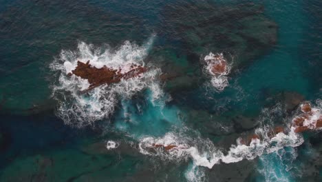 Antena-Arriba-Abajo-Rocas-Sumergidas-Olas-Rompiendo-En-Agua-Turquesa-Translúcida