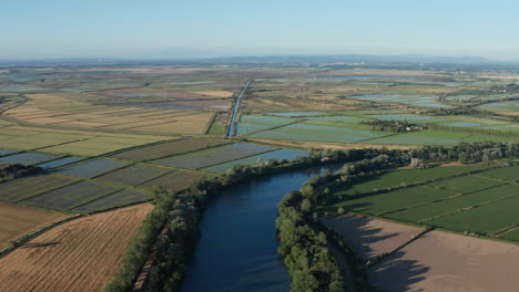 Río-Que-Pasa-A-Través-De-Campos-De-Arroz-De-Camargue-Toma-Aérea-Francia-Puesta-De-Sol