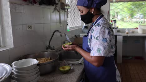 ethnic female chef with cut avocados in kitchen