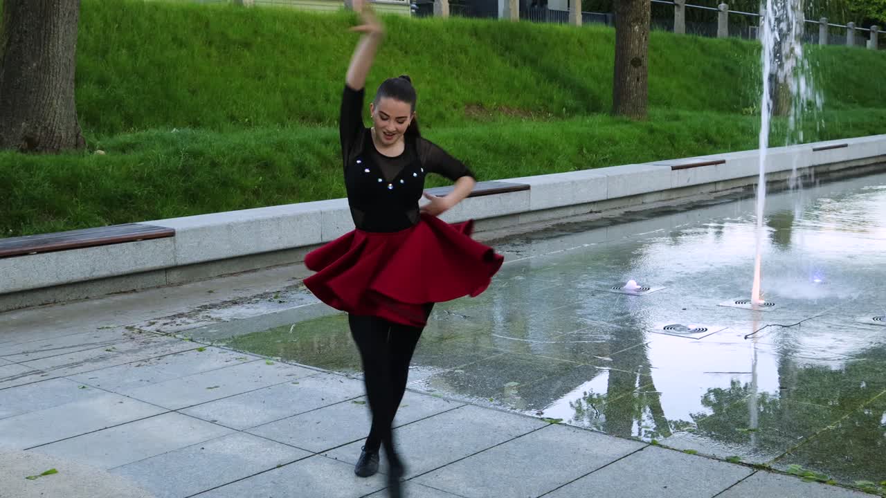 Female does a dance routine outside next to a fountain