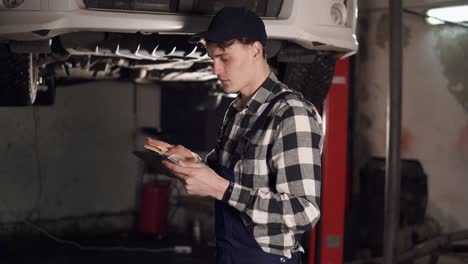 mecánico en un centro de servicio de reparación de automóviles usando una tableta digital