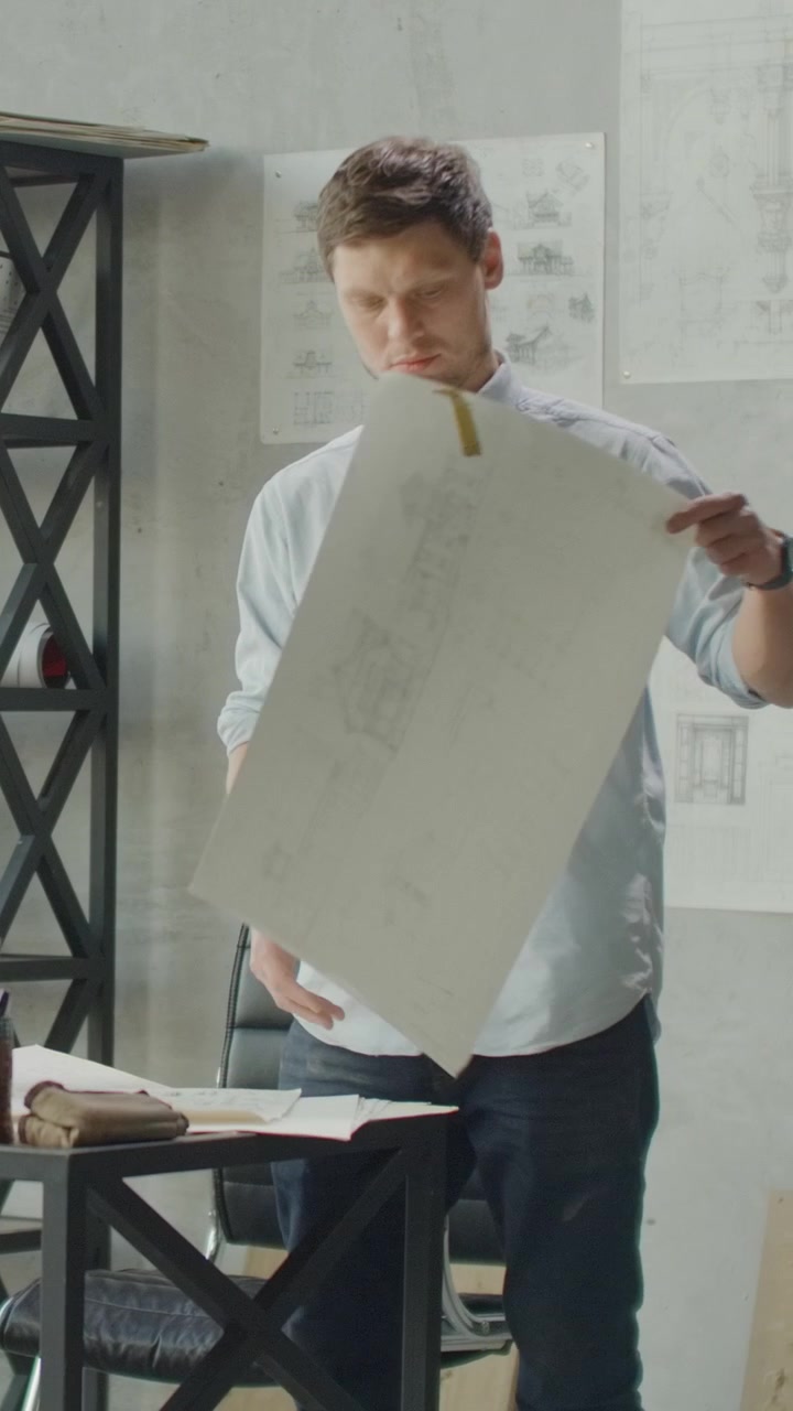 Architect Reviewing Technical Blueprints in Modern Office