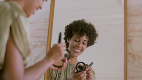 glückliche schwarze frau, die make-up macht und puder auf ihr gesicht aufträgt