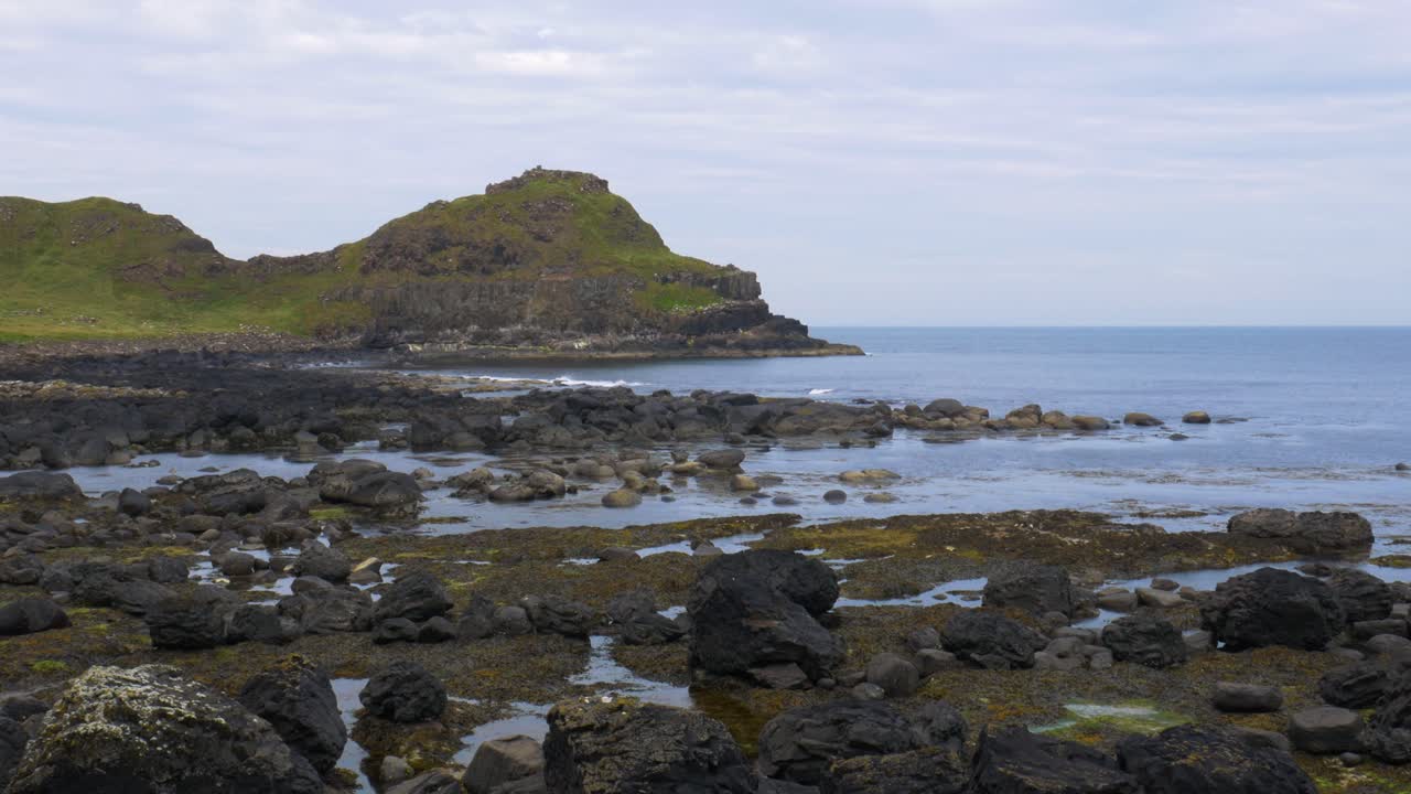 olas en la costa rocosa cerca de las montañas costeras y la calzada del gigante en el condado de antrim, irlanda del norte