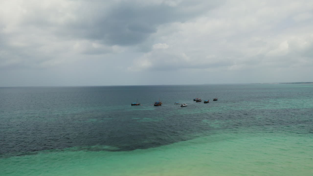 Barcos pesqueros anclados frente a la costa en una playa de arena blanca de Zanzíbar, toma de dron.