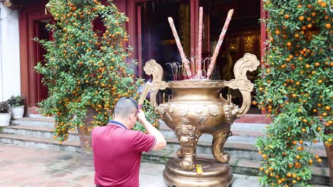 man praying with incense at a temple