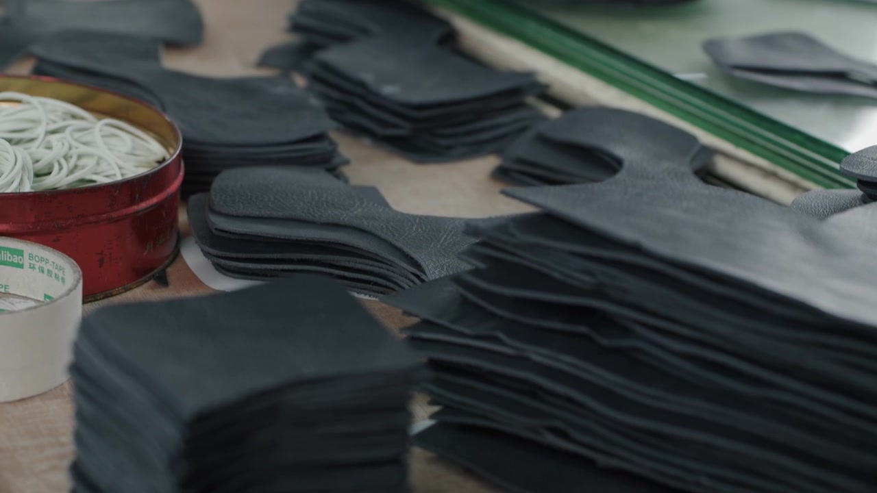 Stacks of cut leather pieces and tools on a workbench in a shoe production workshop