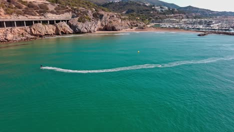 Skate-Surfer-Creando-Ondas-En-Las-Aguas-Turquesas-Cerca-De-Port-Ginesta,-Barcelona,-Vista-Aérea