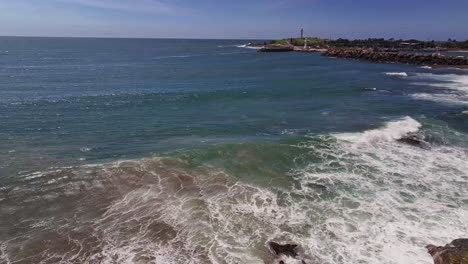 Aerial-rising-up-over-rocks-and-surf-and-revealing-the-light-houses-and-Wollongong-Harbour-beyond