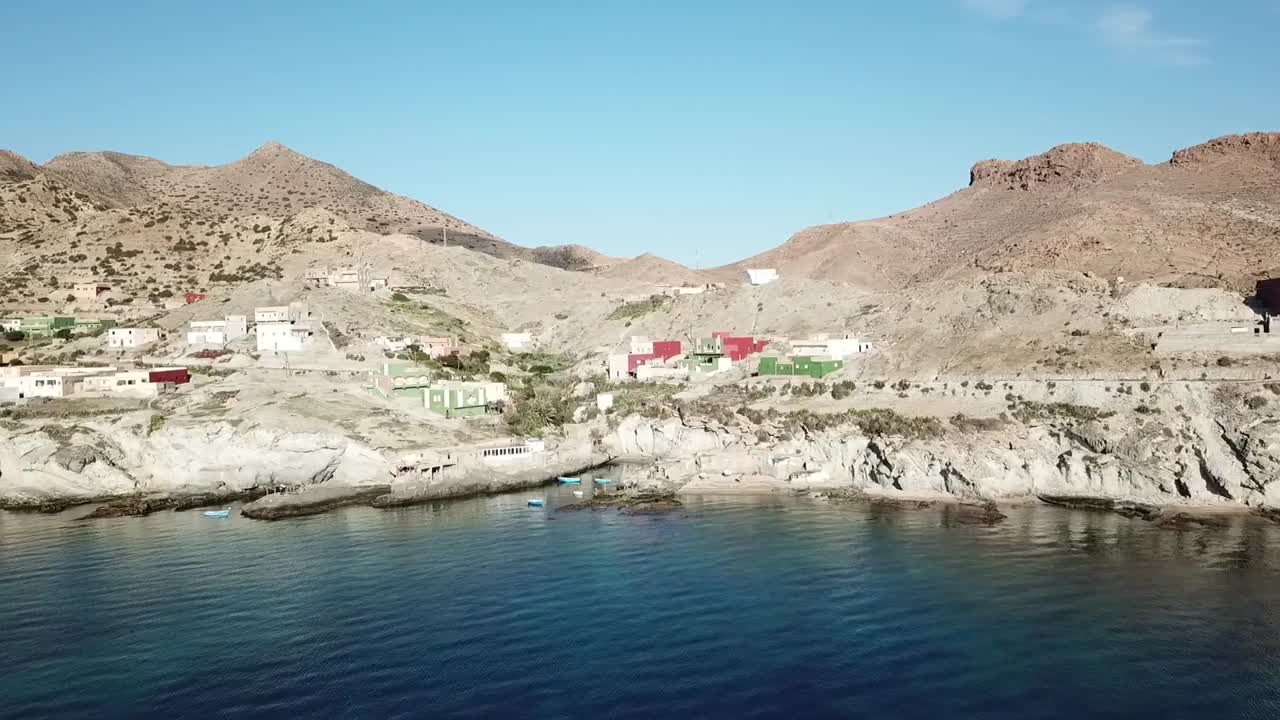 Dynamic drone shot following a flock of white flamingos flying just above the textured surface of a coastal lagoon