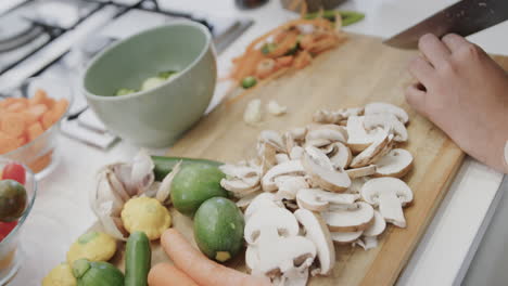 Hands-are-chopping-vegetables-on-a-wooden-board-in-a-home-kitchen