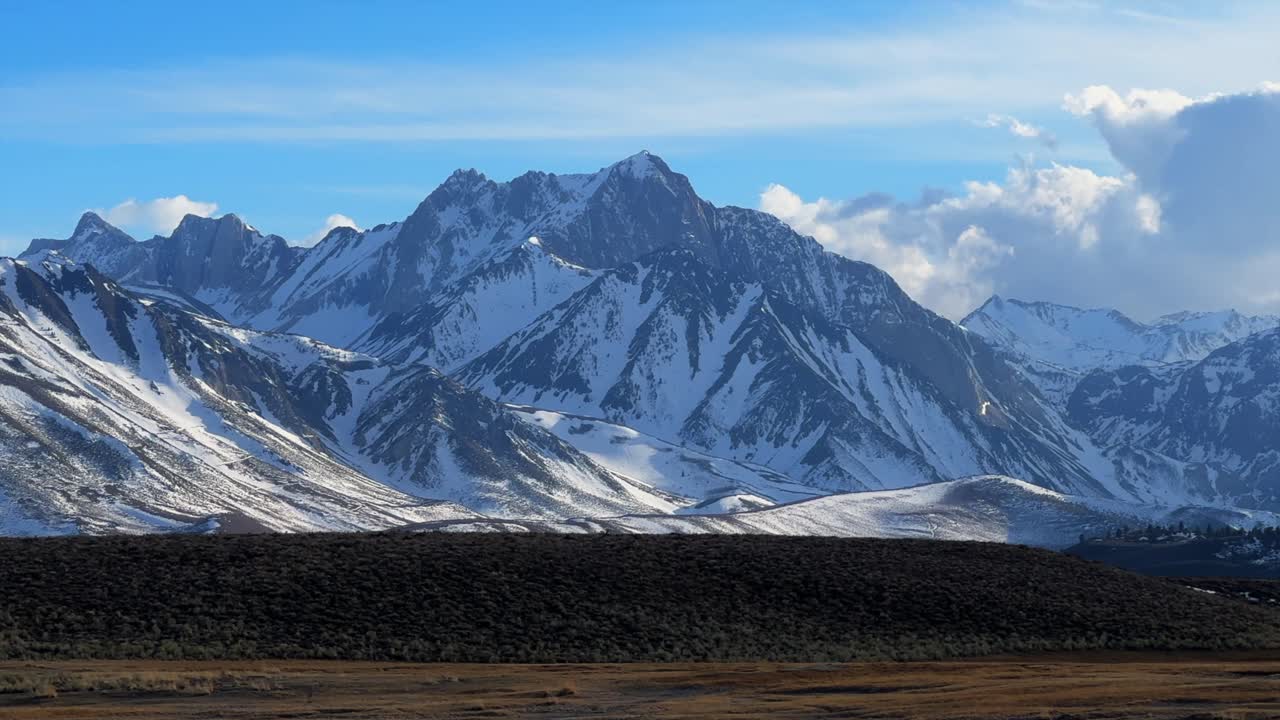 Convict Canyon Lake road natural hot springs view of Sierra Nevada mountains snowy dramatic peaks aerial drone California Benton Crossing Road highway road Mammoth Lakes Mountains pan left motion