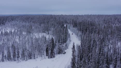 Cars-with-roofbox-driving-on-a-snow-covered-cross-country-road-going-through-Lapland-during-midwinter-solstice