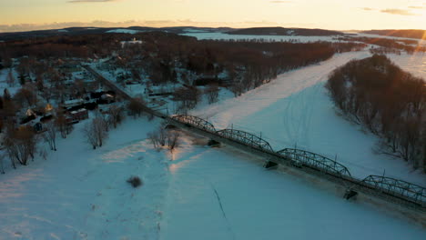 gorgeous aerial drone view of a snow covered river and small town at sunset