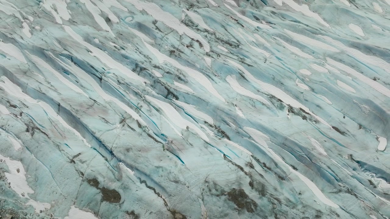 Veduta aerea con drone di crepacci glaciali che rivelano drammatiche texture e formazioni di ghiaccio, motivi ghiacciati e morena in un remoto paesaggio polare