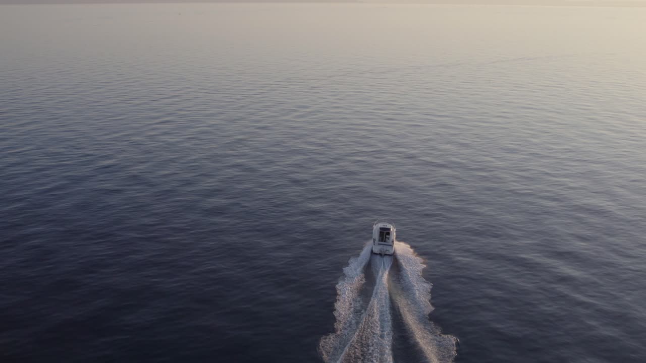 Luftaufnahme goldener Wellen mit einem rasenden Boot in der Abenddämmerung, Split-Dalmatien