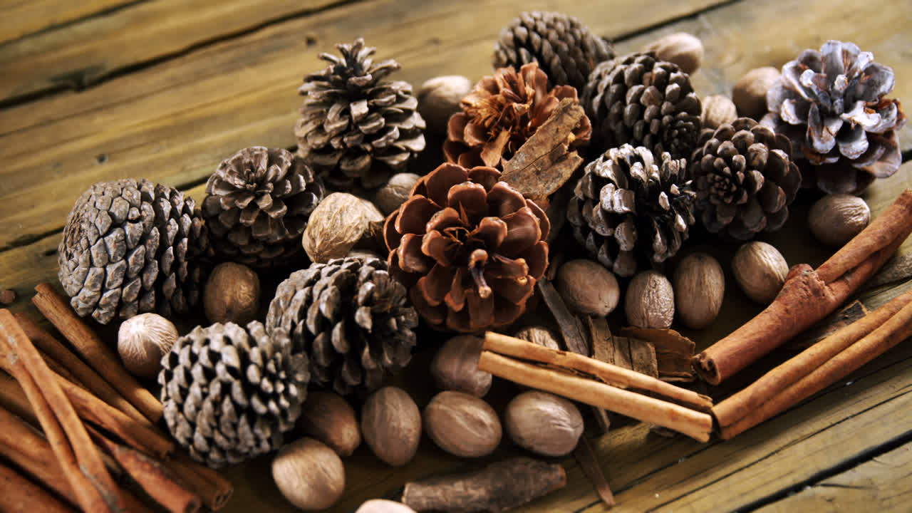 Pine cones and cinnamon sticks on wooden table 4k
