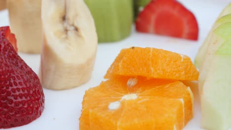 close up of a fruit salad with orange slices, banana slices, strawberries, and green apple slices