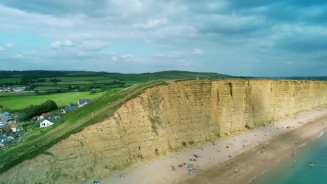 Bridport-West-bay-cliffs-British-seaside-coastline-Dorset-aerial-pull-back-reveal-view