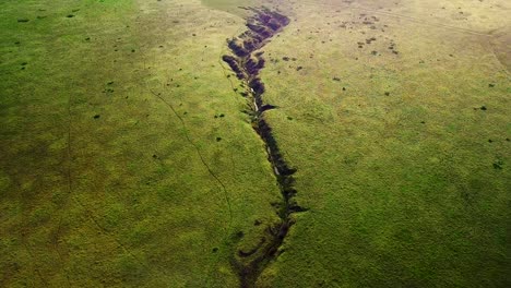 creek runs through green fields and reveal of sunrise over distant hills