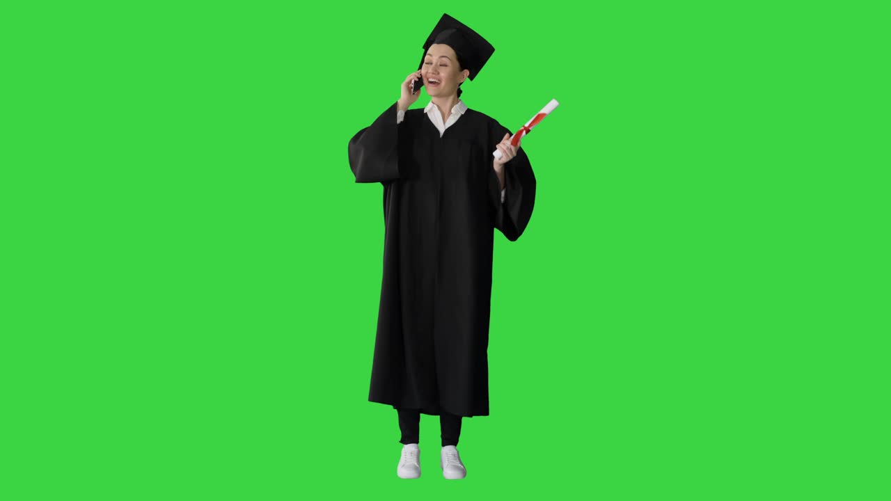 Studentessa emozionata in toga di laurea che parla al telefono tenendo in mano il diploma su schermo verde, Chroma Key