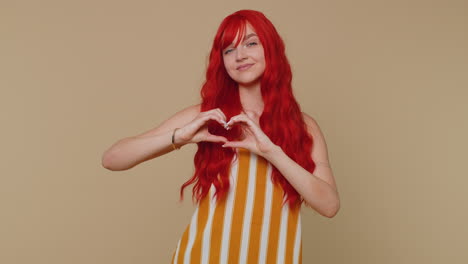 smiling ginger girl makes heart gesture demonstrates love sign expresses good feelings and sympathy