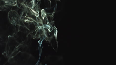 close up of white smoke from candle or incense drifting across frame against black background