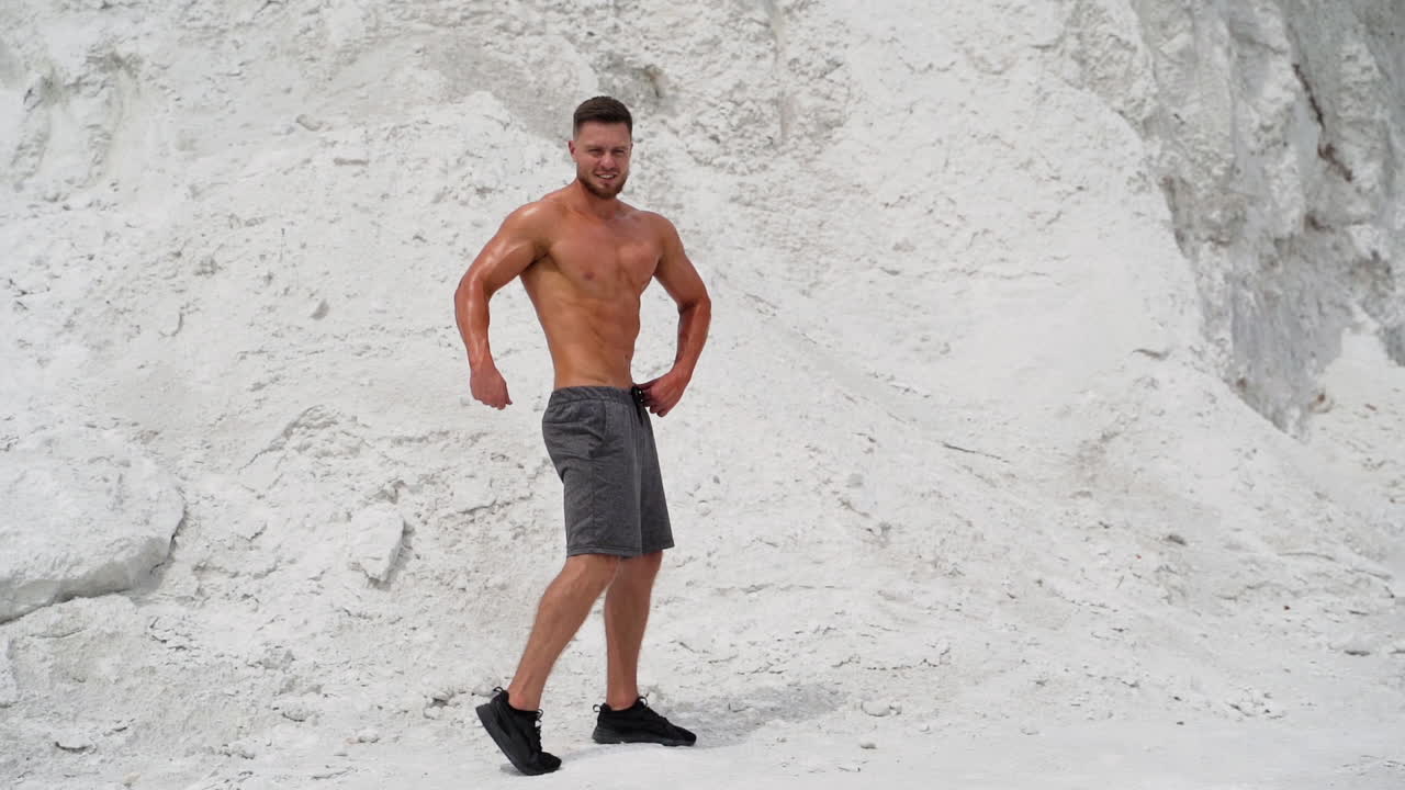 Sport man posing outdoor. Fit muscular young man with naked torso is posing on nature