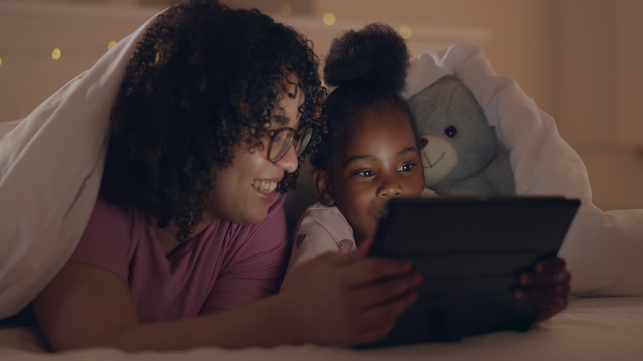 Mother, girl and tablet in bed