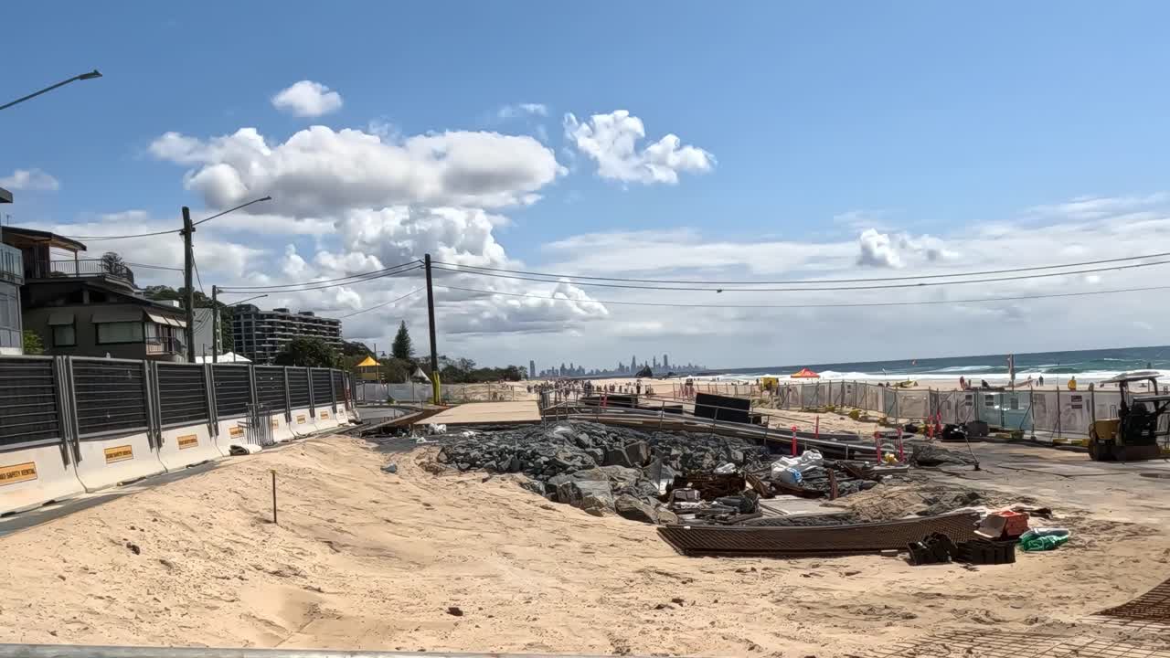 A fenced construction area with a prominent danger sign and sandy terrain under a clear sky.