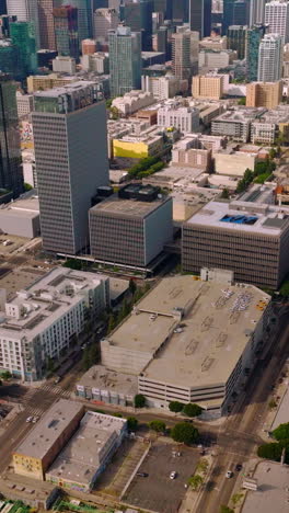 approaching amazing skyscrapers in the financial downtown los angeles, california. drone footage over the city panorama at backdrop of hills and blue skies. vertical video