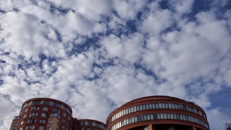 modern apartment building with semicircle rooftops and white cumulus clouds in blue sky above