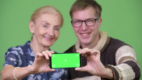 happy grandmother and grandson showing phone together