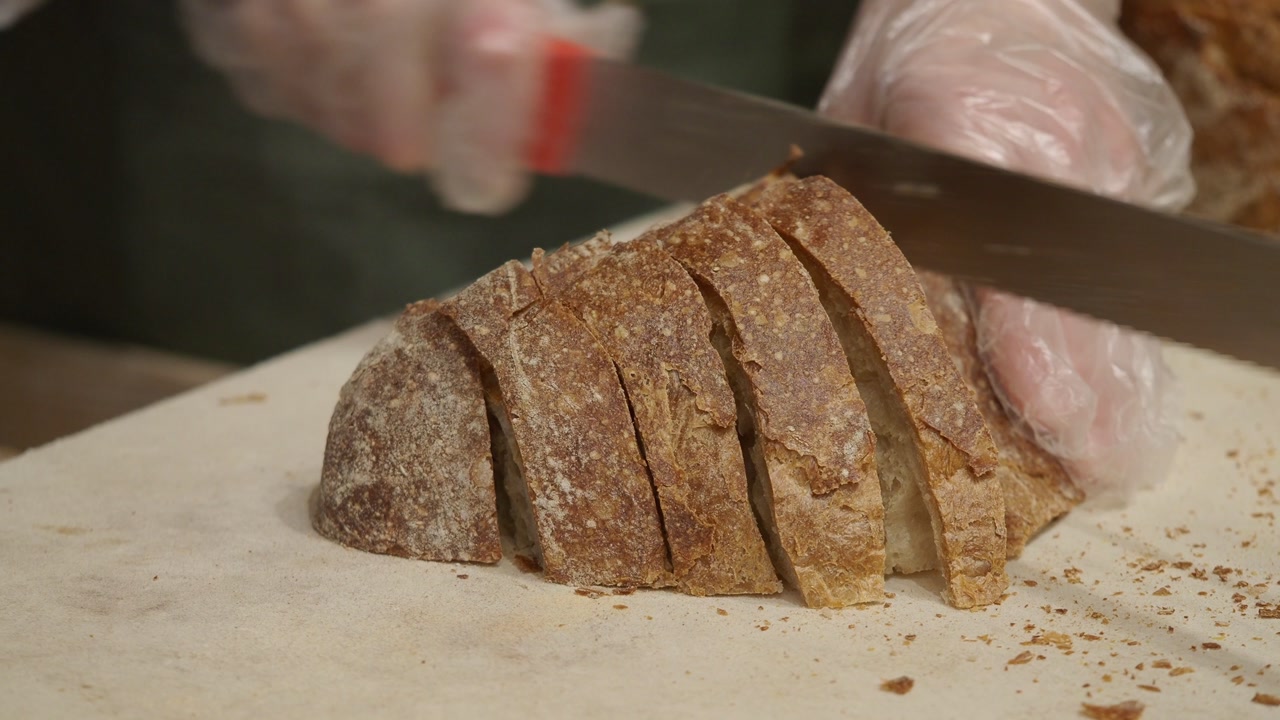 Close-up of Hands Slicing a Loaf of Fresh Bread