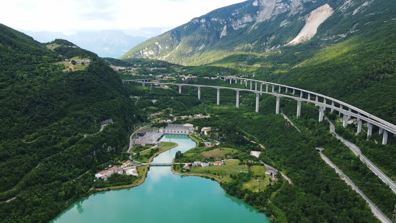 Long viaduct stretches across lush Dolomite valley glowing waters at golden hour