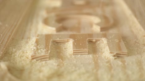 a slow motion macro shot of a carpenter brushing sawdust from wooden sign on a work bench