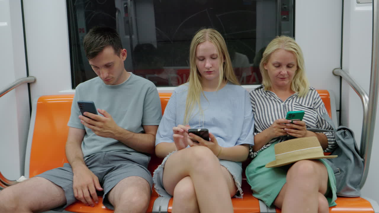Trzy osoby siedzące w pociągu metra, korzystające ze smartfonów, miejski dojazd i cyfrowy styl życia.