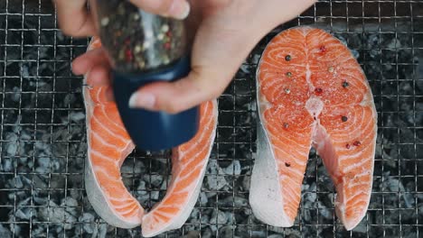 salmon bbq on charcoal grill. close up seasoning salmon steak salt and pepper