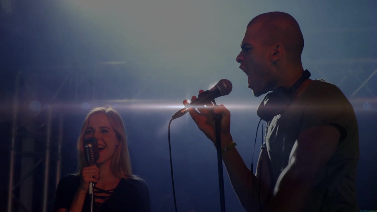 Male singer singing and gesturing on dim stage, backlight causing sparkles, music duet for audience