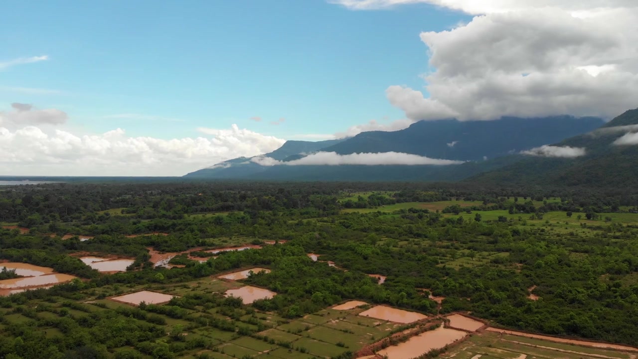 4K-optagelse af en flyvning mod skyerne over rismarker i en fredfyldt dal i Laos, Sydøstasien