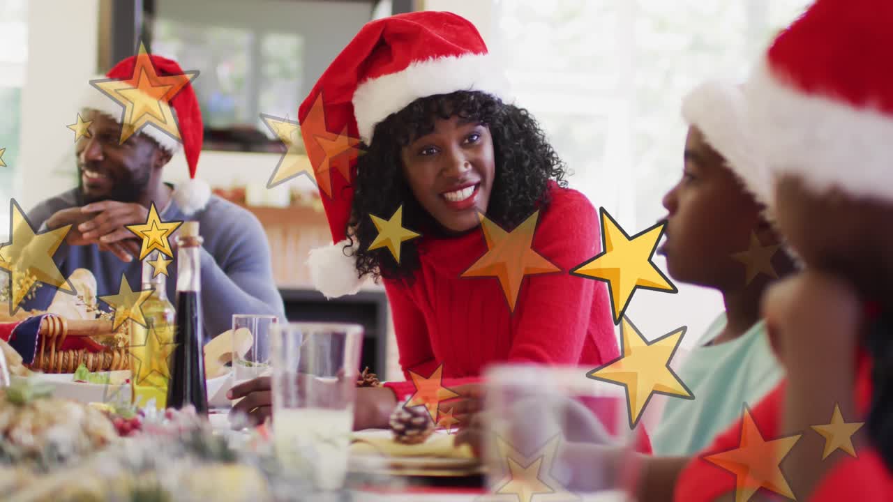 Animação de estrelas sobre família afro-americana com gorros de Papai Noel ceando no Natal.
