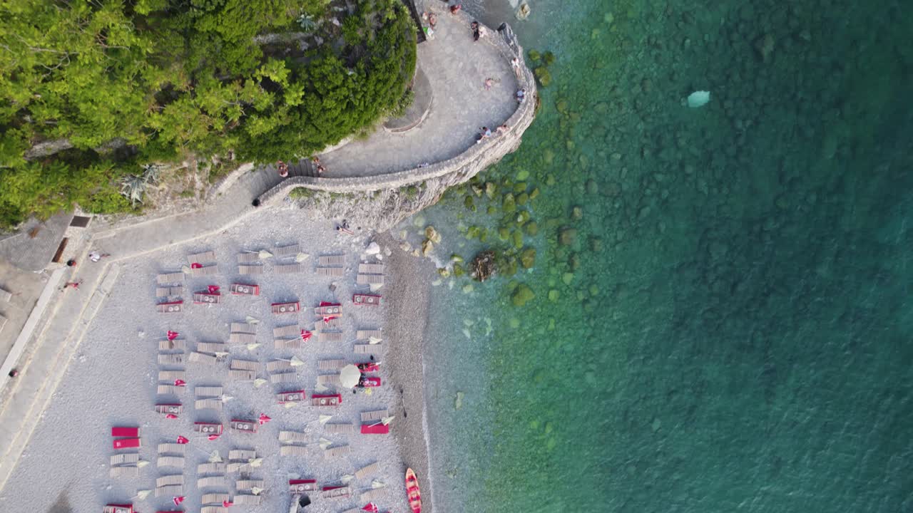 Aerial: Budva-Sveti Nikola Island, Montenegro: turquoise coastline with beach loungers