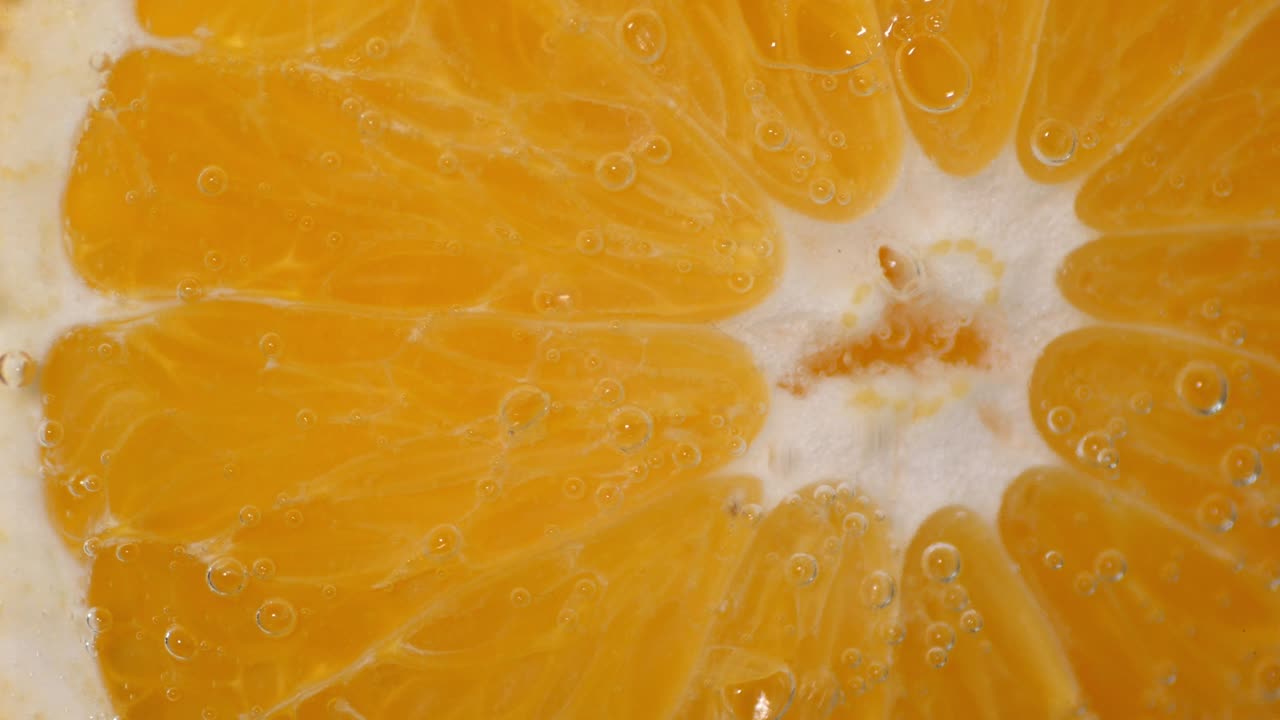 Un pezzo di arancia fresca sott'acqua con bolle d'aria