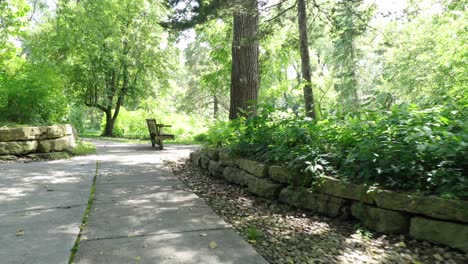 a concrete path cuts through a hill lined with large river rocks up the incline to a bench on the top at a park and nature preserve in la crosse wisconsin