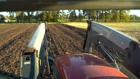 bandada de pájaros se levanta del campo recién cultivado mientras el agricultor conduce un tractor, vista desde la cabina