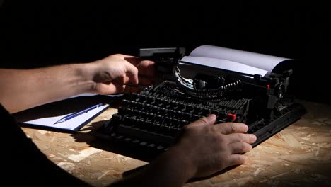 Person Typing on an Old Typewriter in a Dark Room